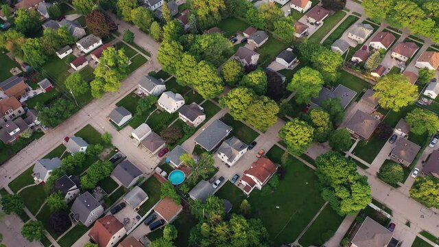 Aerial view of american suburb at summertime.  Establishing shot of american neighborhood. Real estate, top down view of residential houses. Drone shot, from above
