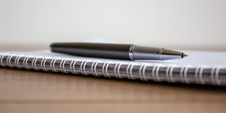 Notebook and pen on beautiful wooden table. Concept background.