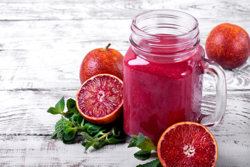 Smoothie with blood orange juice in the mason jar on the white wooden table