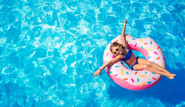 Funny Child On Inflatable Donut In Pool
