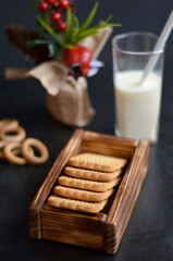 cookies in a wooden box with milk on a black background
