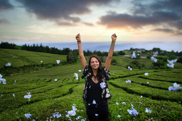 young girl throws petals, flowers scattered in tea field