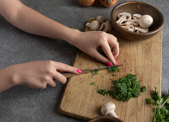 girl's hands chop dill for detox menu. Top view of a chopping board with dill