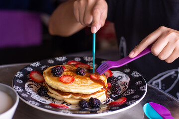 Fototapeta na wymiar A person is eating delicious pancakes with berries