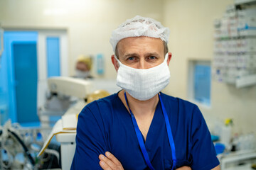 Portrait of the professional surgeon. Doctor wearing mask. Medicinal standng in operation theatre with medical team on the background.