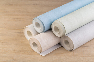 rolls of multi-colored paper wallpaper on a wooden table