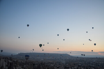 Hot air balloons at sunrise flying in the sky along valleys at Cappadocia of Goreme, Turkey 