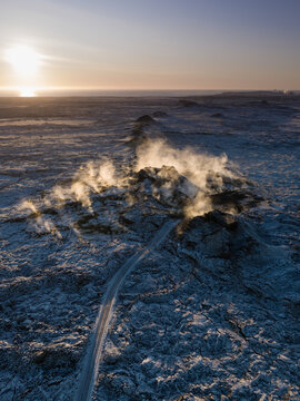 Aerial view of a steaming row of volcanic craters during sunset, releasing geothermal heat centuries after eruption, Eldvorp, Reykjanes Peninsula, Iceland