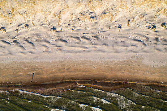 Aerial view of person silhouette shadow standing on Baltic sea shore beach in Klaipeda, Lithuania. Perspective of beautiful nature patterns on surface.
