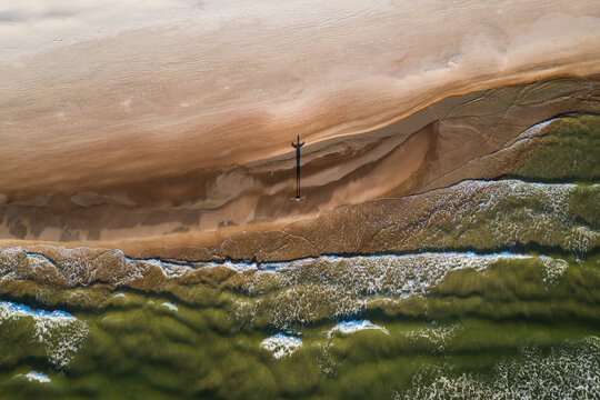 Aerial view of person silhouette shadow standing on Baltic sea shore beach in Klaipeda, Lithuania. Perspective of beautiful nature patterns on surface.