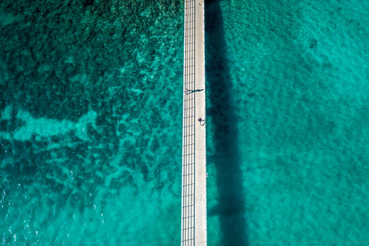 Aerial view of people walking on a bridge surrounded by turquoise water in Vrsar, Croatia