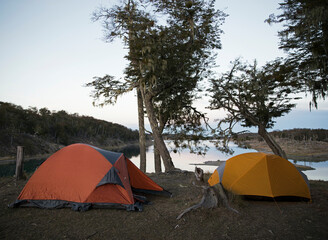 Camping in the wild. Igloo tents in the campsite. Encampment in the forest, besides the lake, at sunrise. 