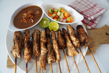 Sate Ayam or Chicken Satay - Indonesian food. Served with peanut sauce and chopped vegetables stock photo