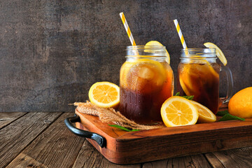 Summer iced tea in mason jars on a wooden serving tray against a dark background
