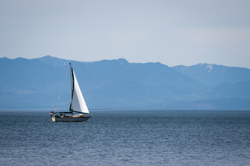 Fototapeta premium Sailing boat with mountains in backdrop, shot on Vancouver Island, British Columbia, Canada