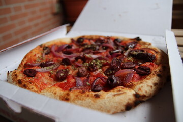 Vegetable italian pizza with olives and onion on tomato sauce inside paper box