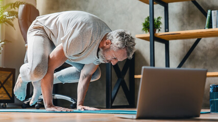 Man in bakasana pose doing vinyasa yoga flow at home. Practising yoga at home