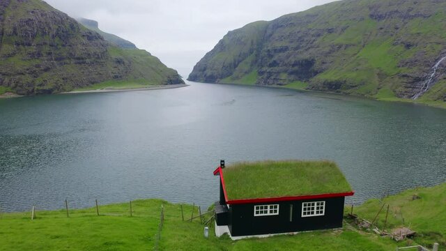 4K video (Ultra High Definition). Gloomy summer view of Saksun village with traditional turf-top house. Evening scene of Pollurin Laguna, Faroe Islands, Denmark, Europe. Traveling concept background.
