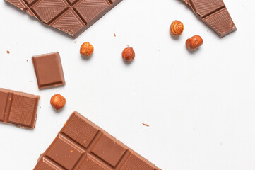 Bar and pieces of milk chocolate, hazelnut on white background flat lay top view copy space....