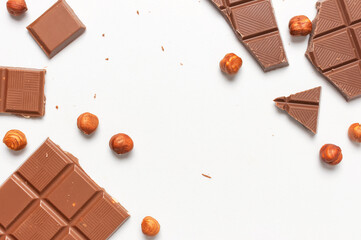 Bar and pieces of milk chocolate, hazelnut on white background flat lay top view copy space....