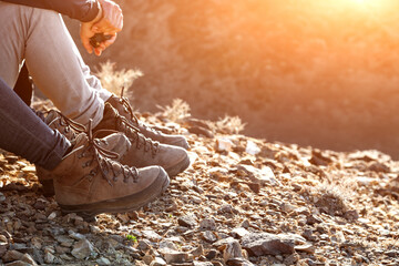 Tourist in trekking hiking boots walking on mountain on sunset