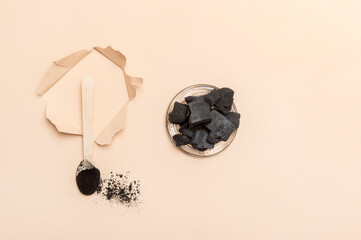 Natural toothpaste activated charcoal in glass jar and bamboo toothbrush on camel color background. Zero waste concept.