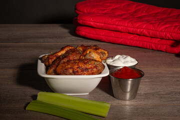 chicken wings in a white dish with sauce and celeri