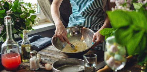 A woman is preparing fresh dough in a cozy atmosphere. Concept of cooking delicious dough dishes at home.