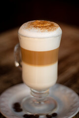 Café capuchino con canela en la espuma sobre una mesa de madera.