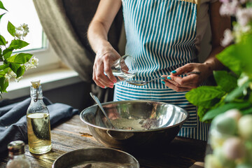 A woman is preparing fresh dough in a cozy atmosphere. Concept of cooking delicious dough dishes at home.