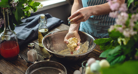 A woman is preparing fresh dough in a cozy atmosphere. Concept of cooking delicious dough dishes at home.