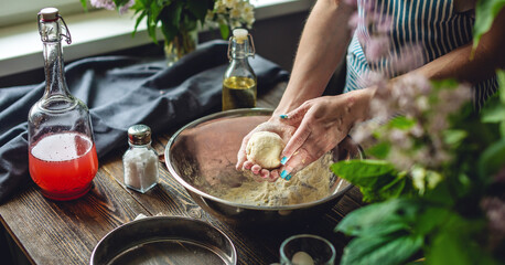 A woman is preparing fresh dough in a cozy atmosphere. Concept of cooking delicious dough dishes at home.