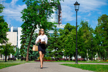 Young business blonde woman walks in a summer park