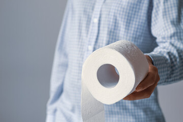 Person in a blue shirt holds out a helping hand with a roll of toilet paper.