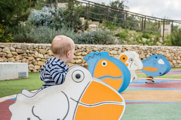 A toddler uses a spring rider in a playground 