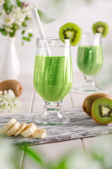 Fruit smoothie with kiwi and banana on a white wooden table