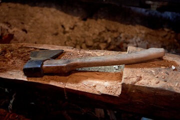 An old axe is lying on a log during the repair of a wooden house.