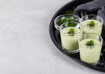 Obraz na płótnie Canvas Dessert cream Panna cotta with green matcha tea in a glass on a light background copy space