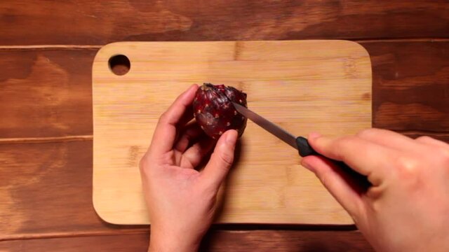 Manos pelando una pitaya fruta exotica mexicana en tabla de bamb&uacute; con cuchillo de mano para postre 