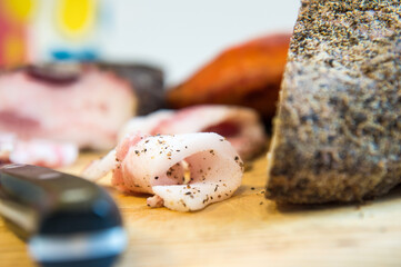detail of a very fat rolled slice of bacon called guanciale in Italy with a colored and blurred background