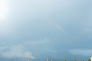 Soft rainbow in the blue sky over the city