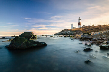 Lighthouse beacon sitting on a cliff overlooking the ocean during sunset. Montauk State Park, New York