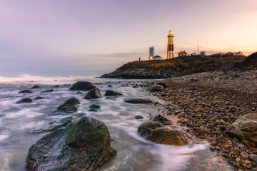 Lighthouse lit up with Christmas lights in a winter seascape along a rocky coast. Montauk State...