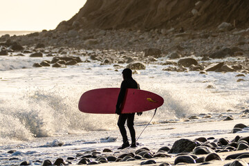 Fototapeta na wymiar Surfer watching waves crashing on a rocky shore. Montauk Point, New York