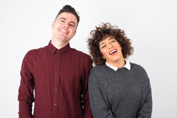 Horizontal portrait of pleasant-looking Caucasian man and woman wearing brown sweater covering her face with hair looking happily to the camera.