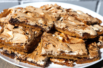 Oblong pieces of home-made crumble cake with strawberry jam covered with meringue served on wooden table. Streuselkuchen, idea for baking, close-up