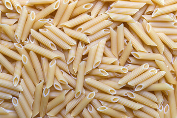 Scattered and uncooked penne texture. Pastry pattern, food background, texture idea