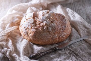 Fresh homemade bread and an old knife on the table. Selective focus