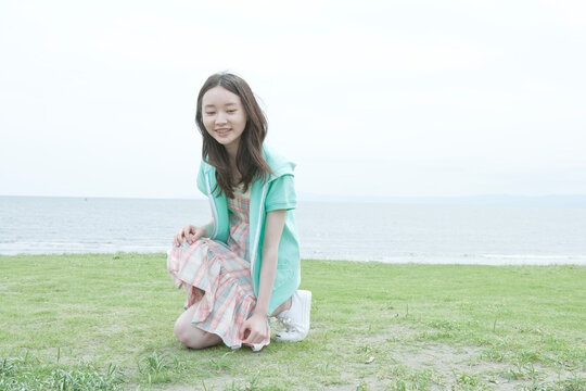 野原にしゃがむ10代の女の子