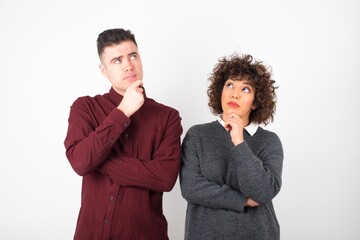 Portrait of thoughtful  woman keeps hand under chin, looks away trying to remember something or listens something with interest, dressed casually, poses indoors. Youth concept.